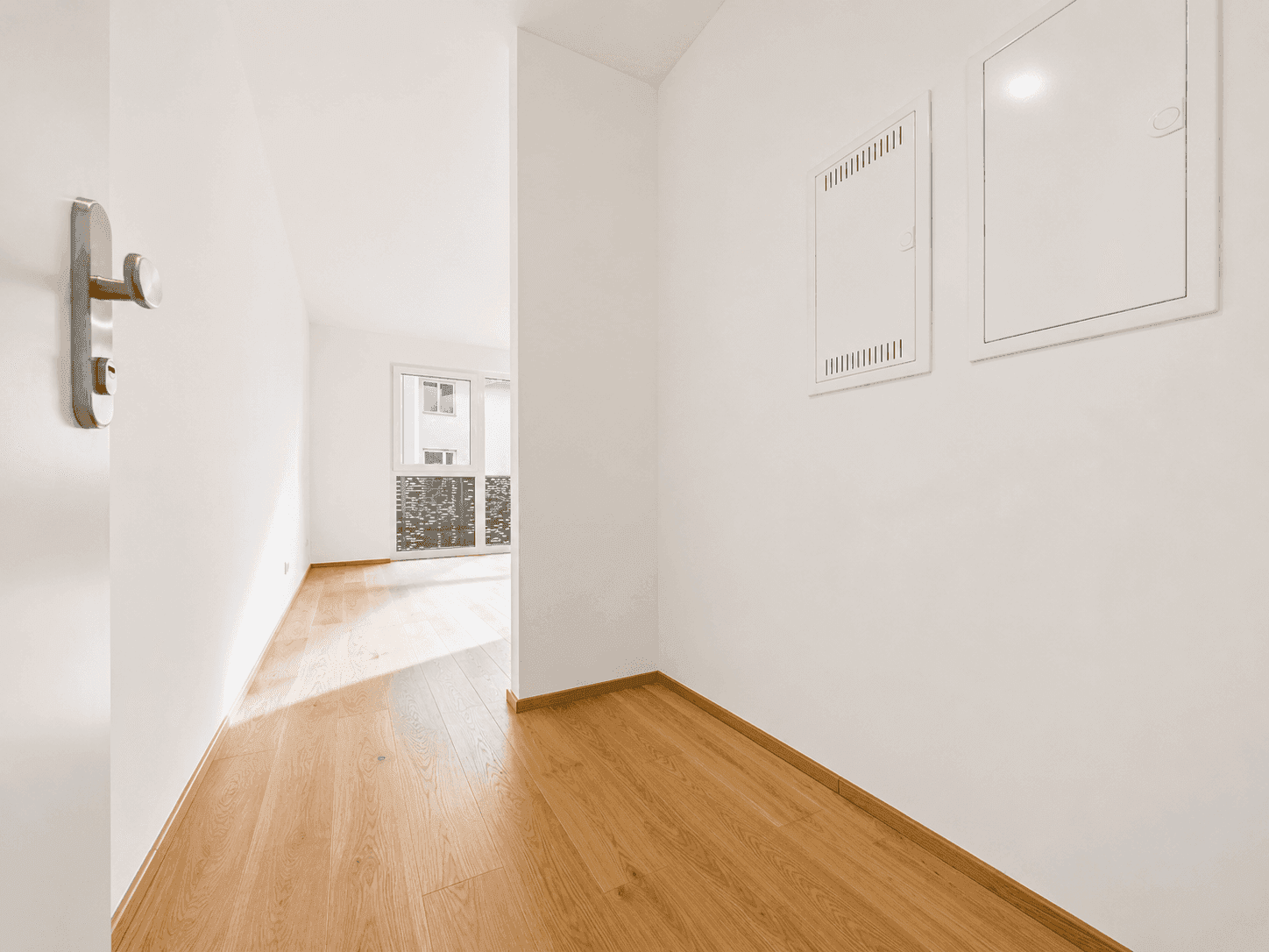 Heller Eingangsbereich mit Holzboden und Blick in einen weiteren Wohnraum.