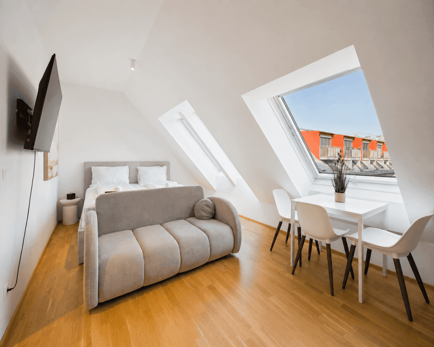 Helles Schlafzimmer im Dachgeschoss mit gemütlichem Sofa, Esstisch und Dachfenstern.