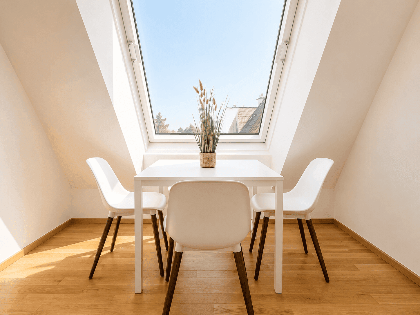 Heller Essbereich mit kleinem Tisch, Stühlen und einem großen Dachfenster.