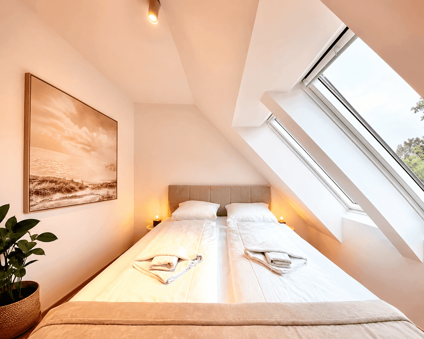Gemütliches Schlafzimmer im Dachgeschoss mit Doppelbett, Dachfenster und moderner Dekoration.