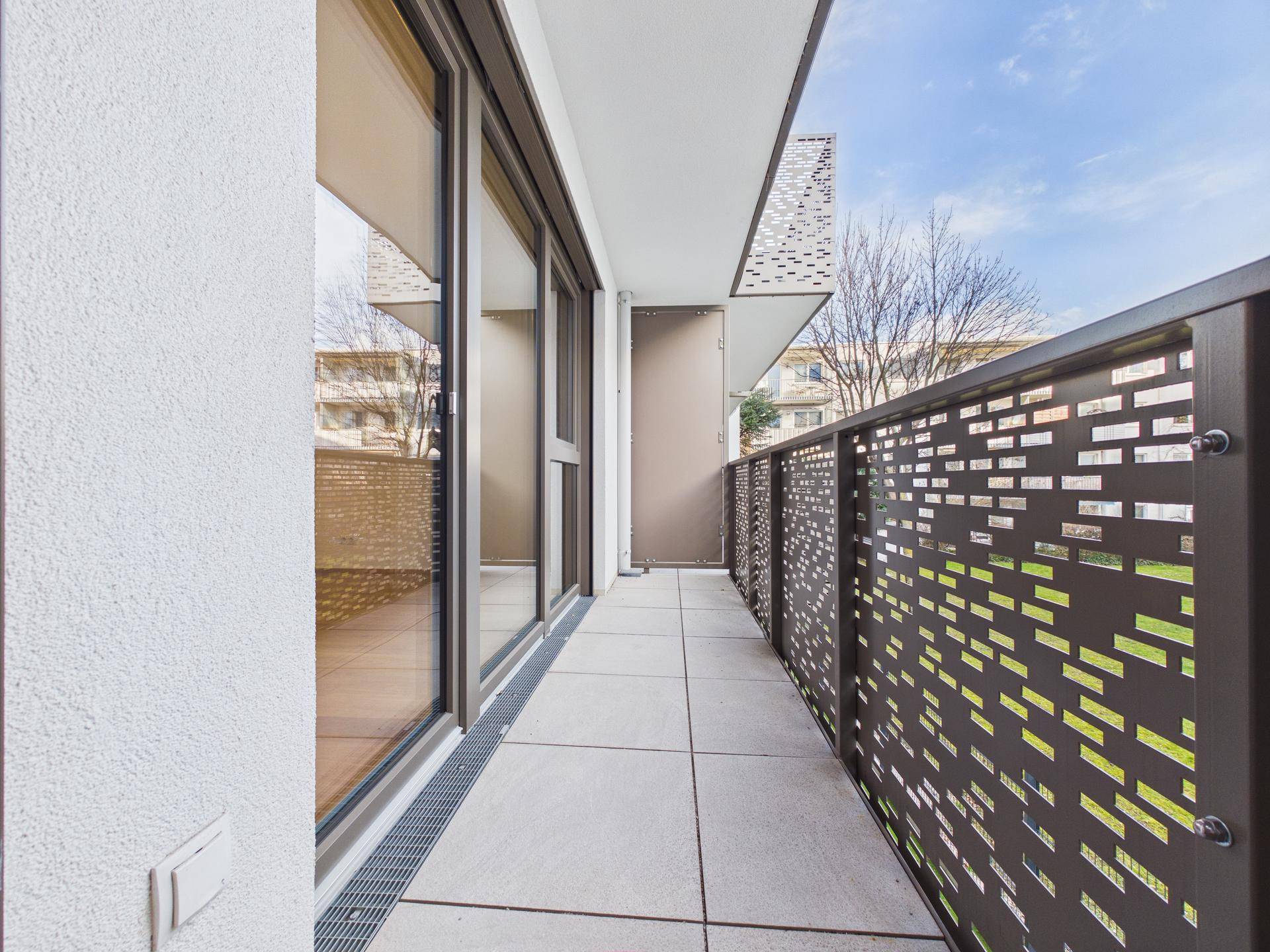 Langer, schmaler Balkon mit Fliesenboden und modernem Metallgeländer, zugänglich vom Innenraum.