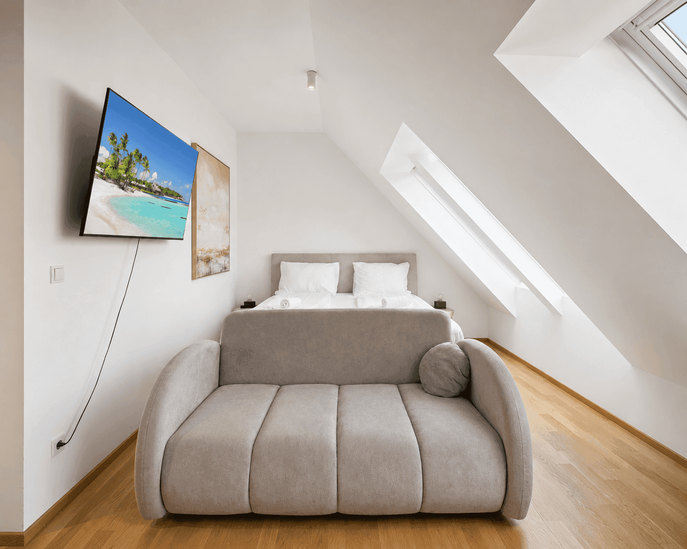 Gemütliches Schlafzimmer im Dachgeschoss mit Doppelbett, Sofa und schrägen Wänden.