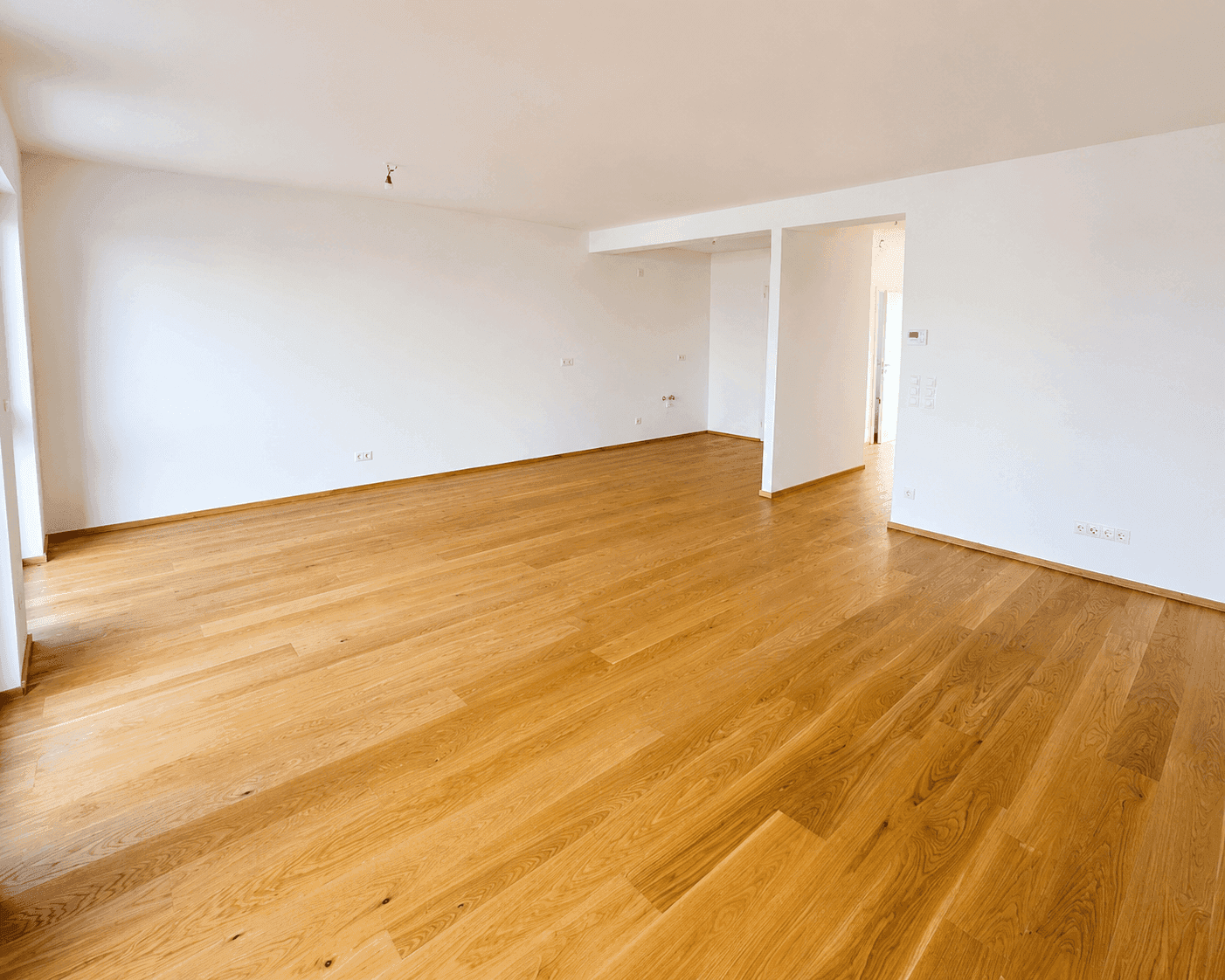 Großer, heller Wohnbereich mit Holzboden und viel Platz für individuelle Gestaltung.