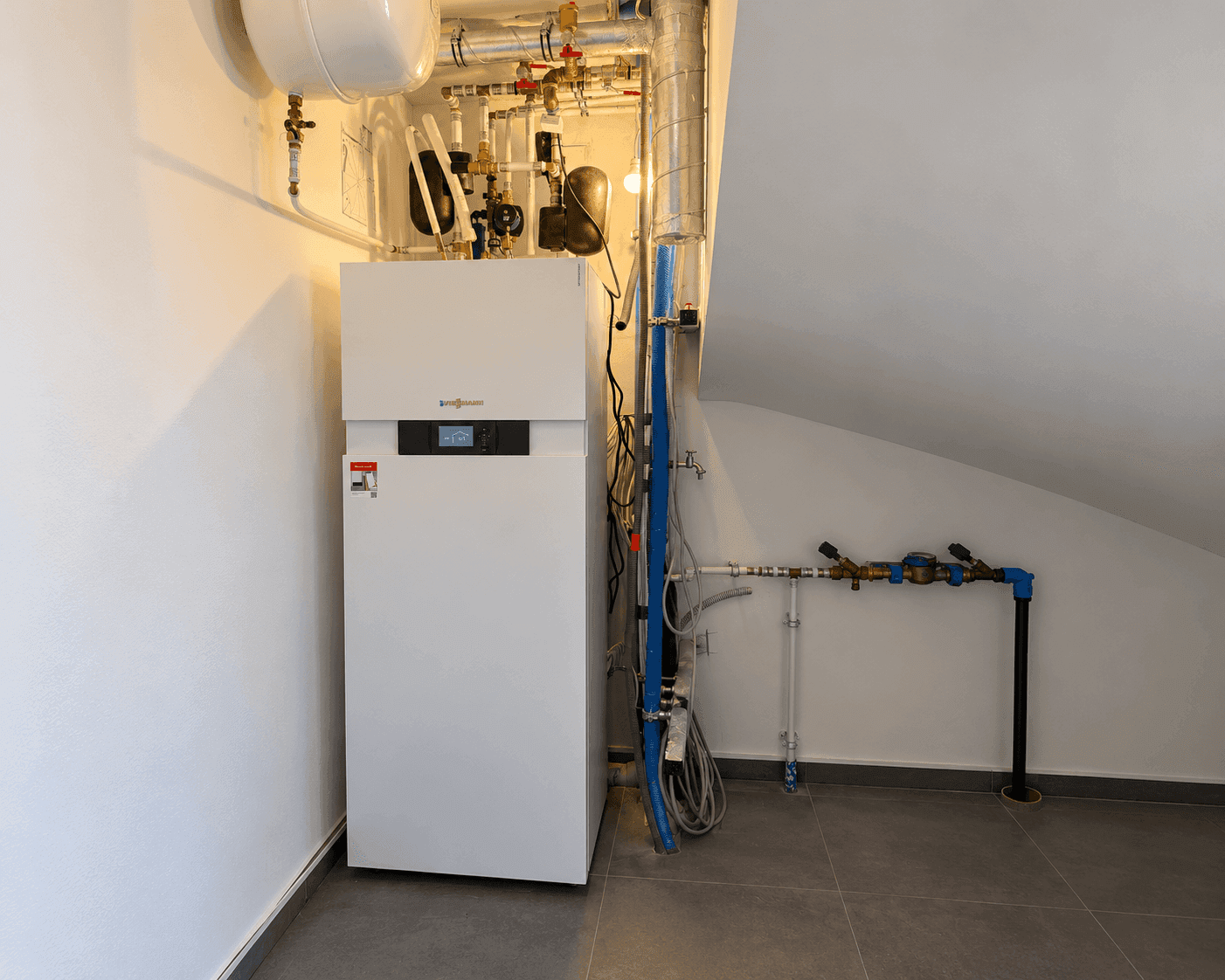Heizungsraum mit moderner Viessmann Anlage und sichtbaren Rohrleitungen unter einer Dachschräge.