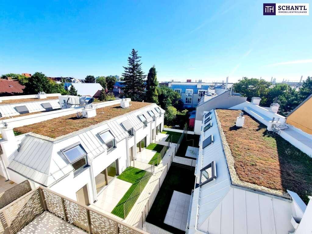 Luftaufnahme einer modernen Wohnanlage mit begrünten Dächern und Innenhofbereich unter strahlend blauem Himmel.
