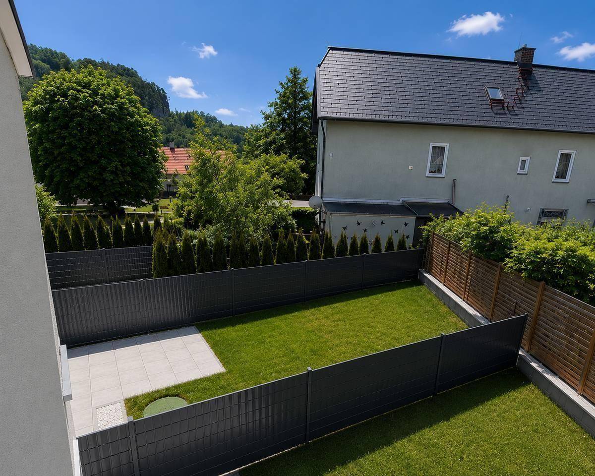 Vogelperspektive auf den privaten Garten mit Rasenfläche und gepflasterter Terrasse.