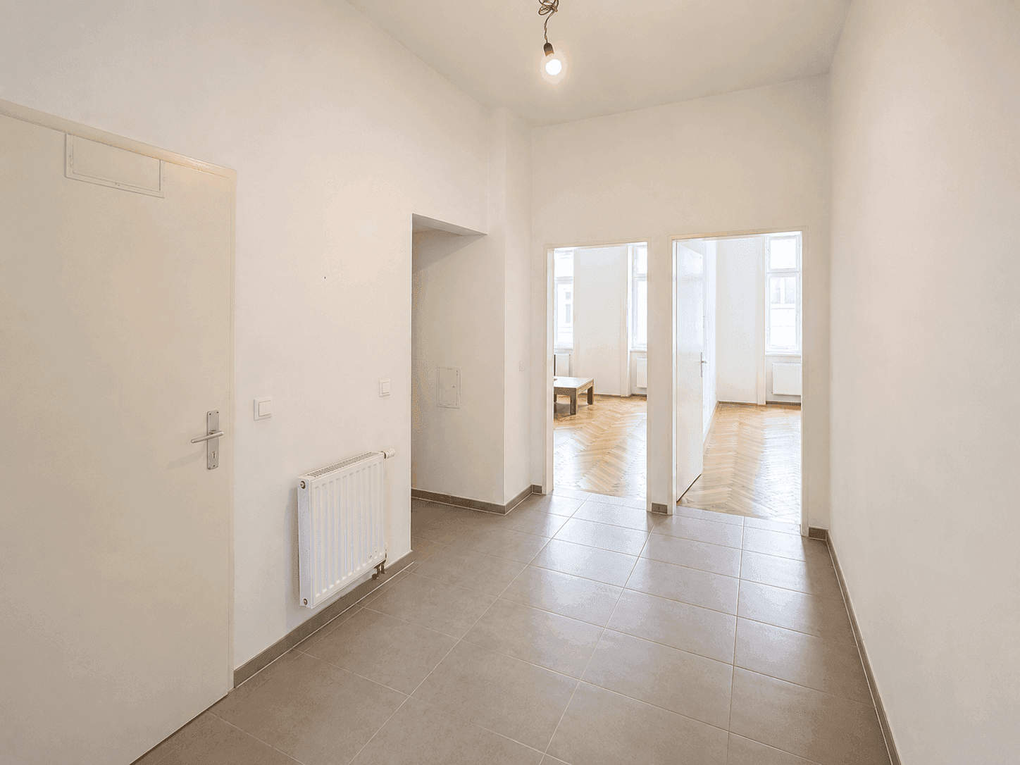 Geräumiger Eingangsbereich mit Fliesenboden und Blick in angrenzende Zimmer mit Parkett.