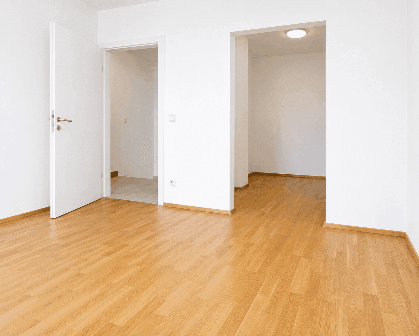 Geräumiges, helles Zimmer mit Holzboden und zwei Türöffnungen, bietet flexible Nutzungsmöglichkeiten.
