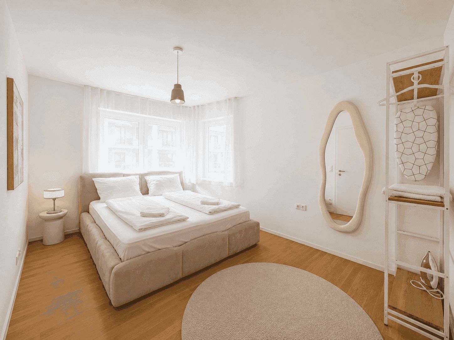 Gemütliches Schlafzimmer mit großem Bett, Holzboden und viel Tageslicht.