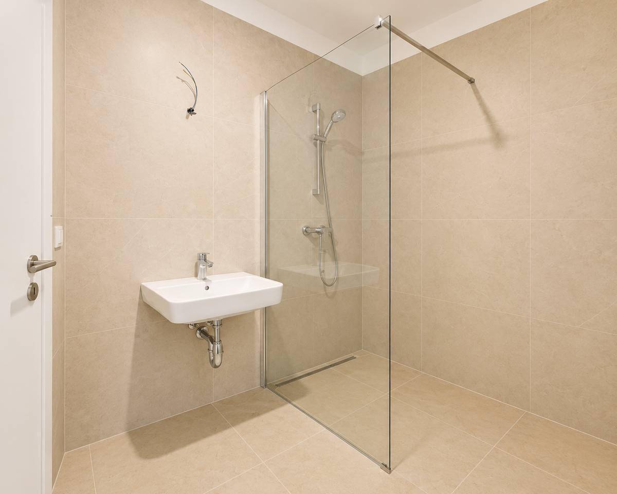 Helles Badezimmer mit ebenerdiger Dusche, Glasabtrennung und modernem Einzelwaschbecken.