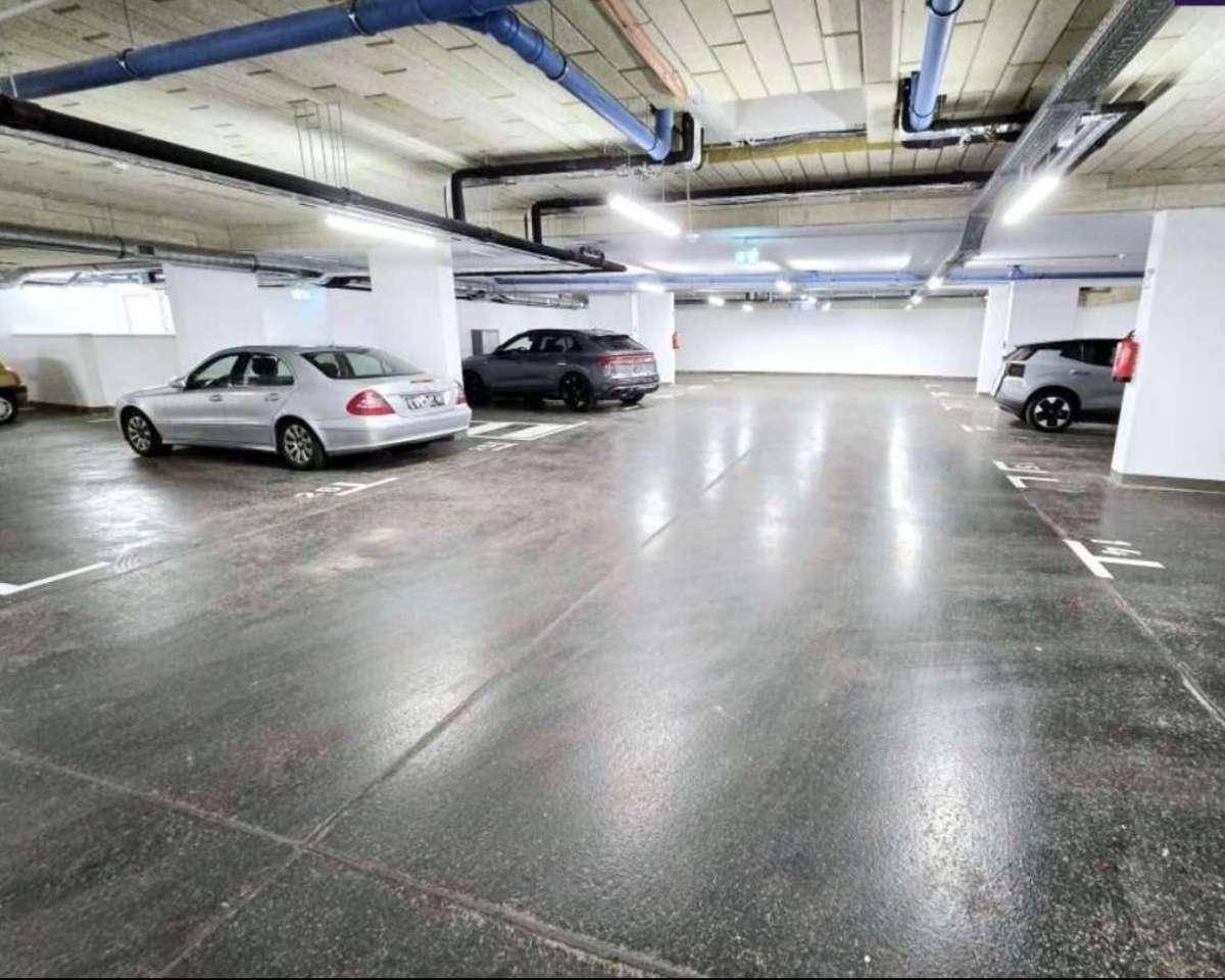 Geräumige Tiefgarage mit markierten Parkplätzen und mehreren abgestellten Fahrzeugen.
