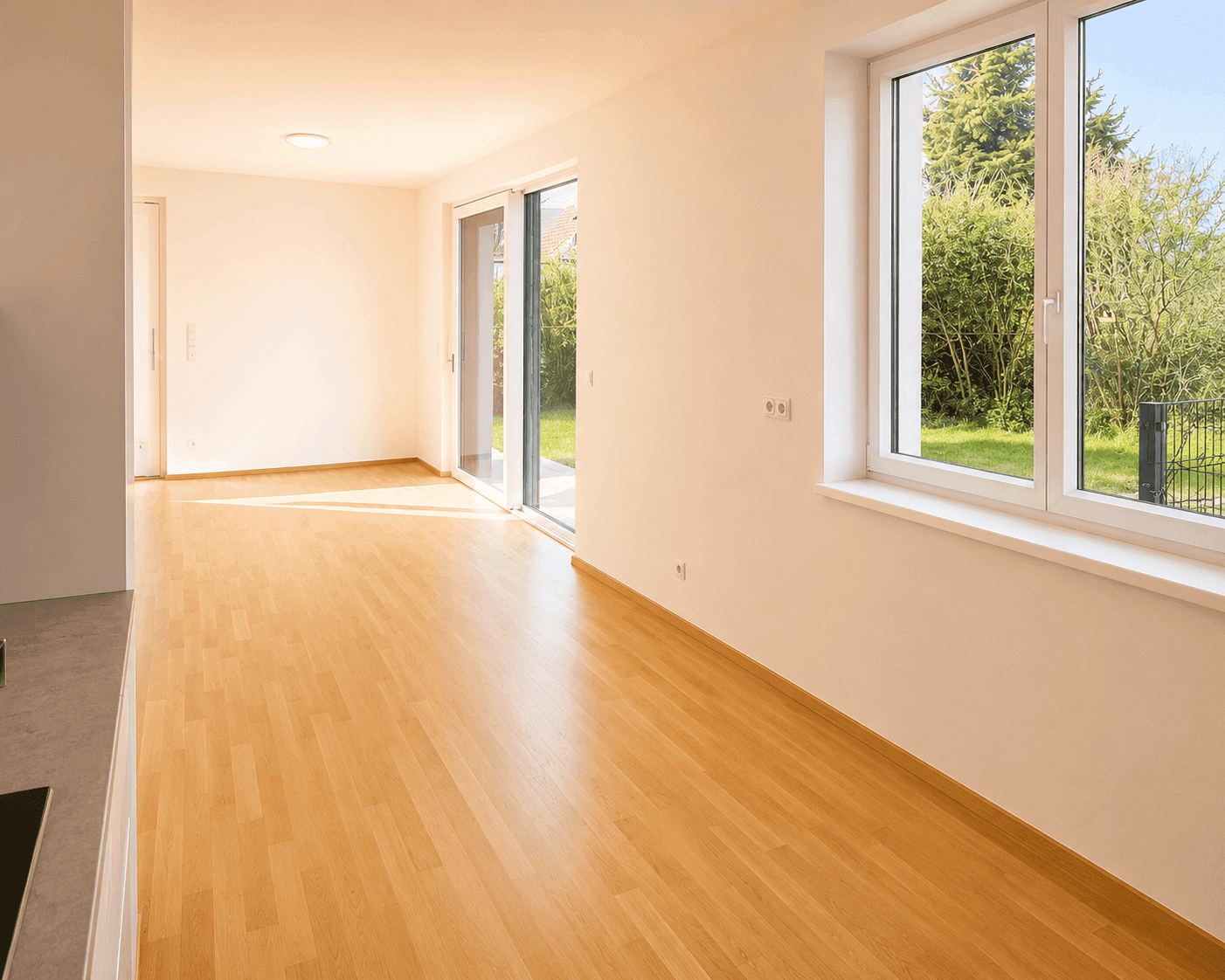 Heller Wohnbereich mit Holzboden, großen Fenstern und Schiebetüren zum Garten.