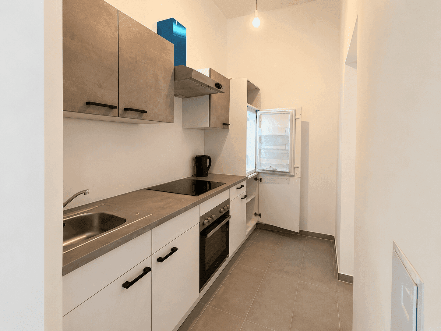 Moderne Einbauküche mit hellen Fronten, Induktionskochfeld und integriertem Kühlschrank.