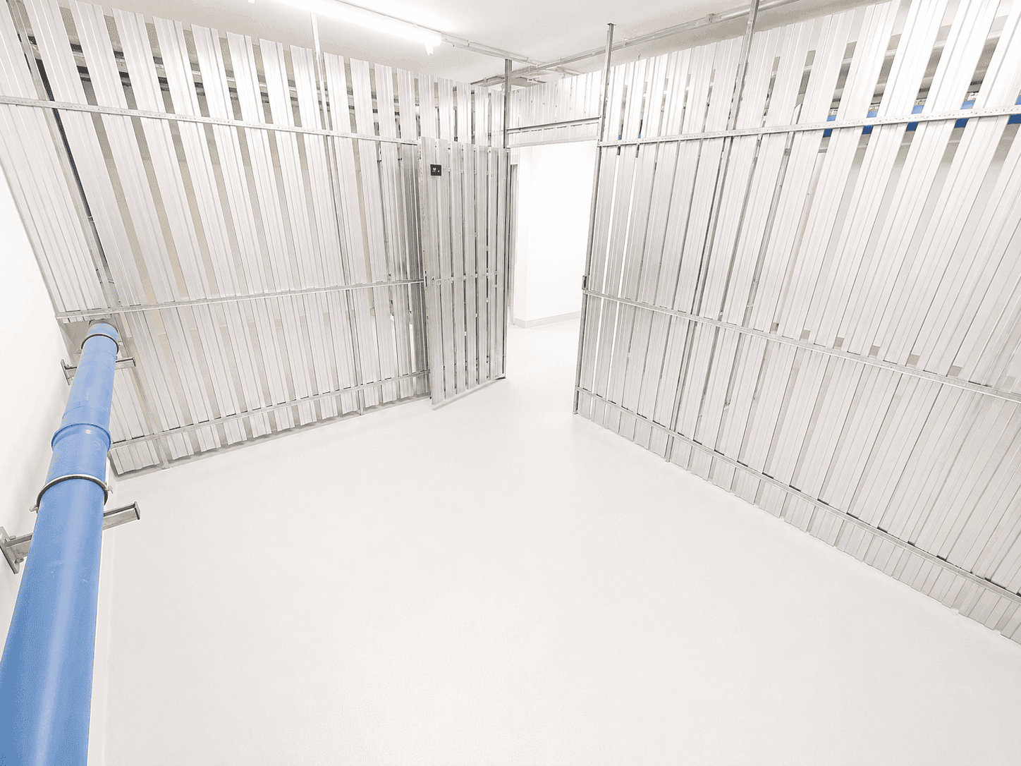 Geräumiger Abstellraum mit Metallabtrennungen und hellem Boden in einem Kellerbereich.