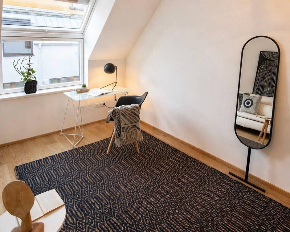 Helles Arbeitszimmer im Dachgeschoss mit Holzboden, Dachfenster und modernem Schreibtisch.