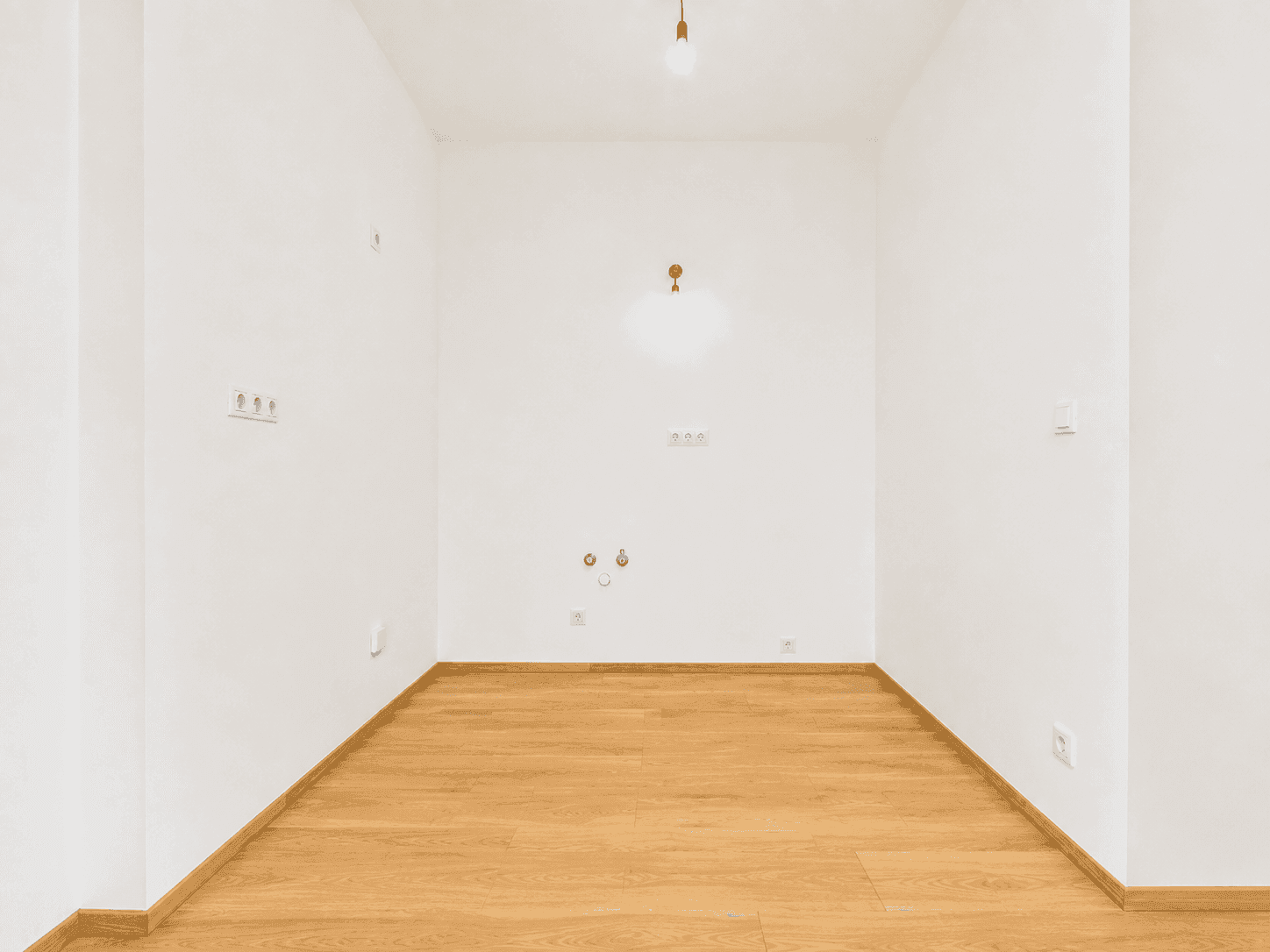 Leerer Küchenbereich mit Anschlüssen für Spüle und Herd, bereit für den Einbau einer modernen Küche.