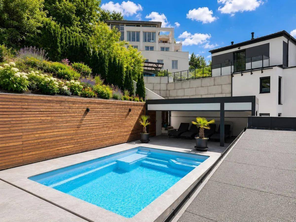 Außenbereich mit modernem Pool, Holzverkleidung und Liegeflächen unter einem Carport.