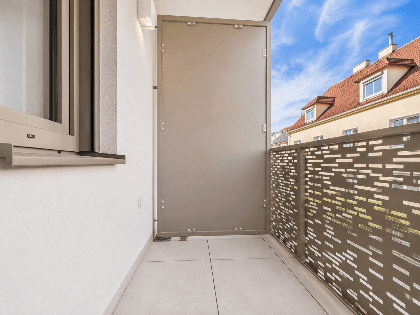 Moderner Balkon mit perforierter Metallbrüstung und Blick auf die umliegenden Gebäude.