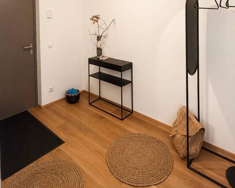 Moderner Eingangsbereich mit Holzboden, minimalistischer Konsole und Garderobe.