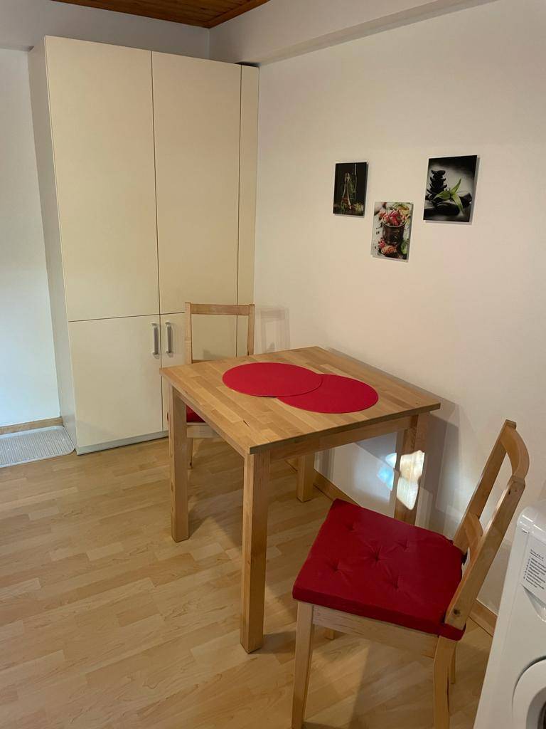 Heller Essbereich mit Holztisch, roten Stühlen und praktischen Wandschränken.