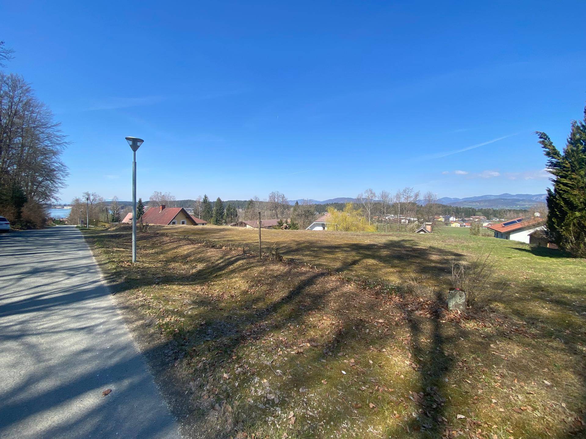 Weitläufiges Grundstück mit Straße, Laterne und Blick auf den See sowie die umliegende Landschaft.