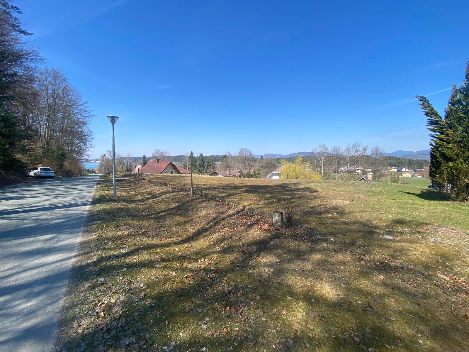 Weitläufiges Grundstück mit Straße, Laterne und Blick auf den See sowie die umliegende Landschaft.