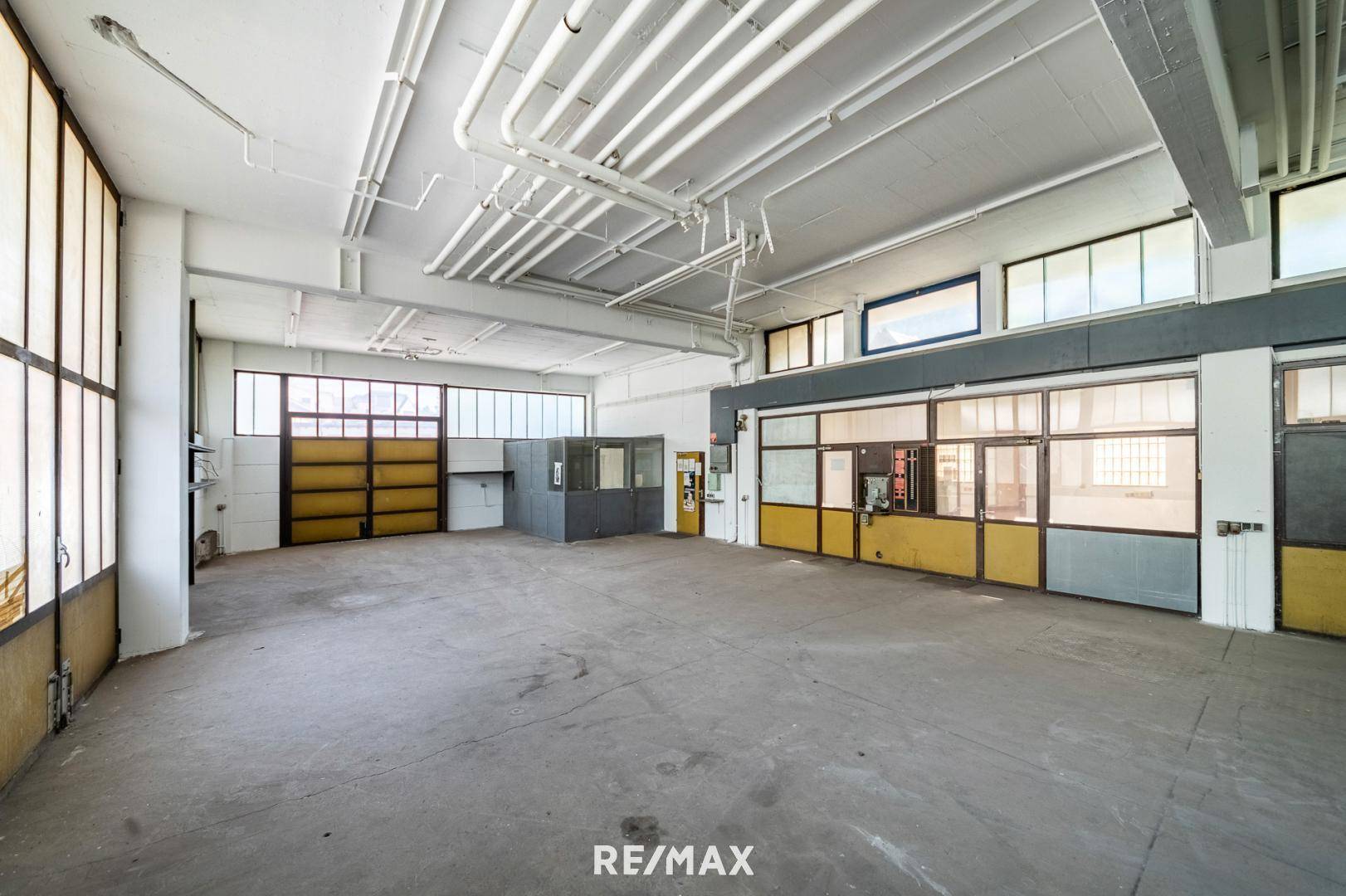 Großer, heller Gewerberaum mit Betonboden, hohen Decken und flexiblen Trennwänden für verschiedene Nutzungen.