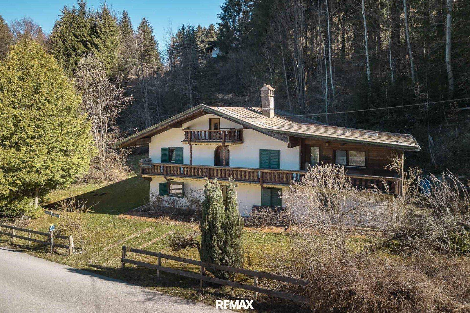 Traditionelles Landhaus mit charakteristischen Holzelementen und Balkonen in sonniger Lage.