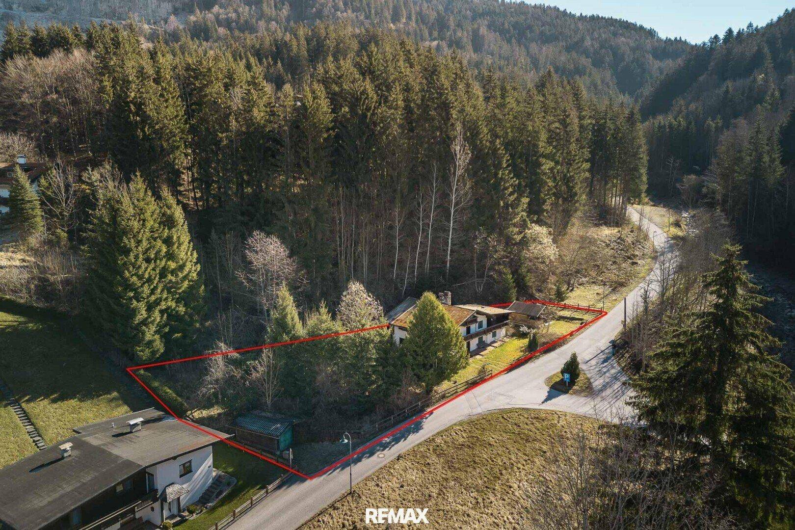 Weitläufige Luftaufnahme des Anwesens, eingebettet in eine grüne Hügellandschaft mit Wald.