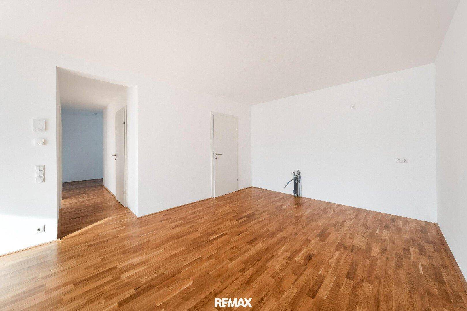 Leerer Raum mit Holzboden und weißen Wänden, der auf weitere Nutzung wartet.