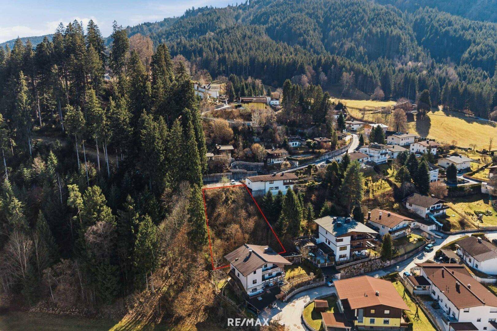 Luftaufnahme eines Grundstücks in einer Siedlung am Hang mit Blick auf die umliegende Natur.