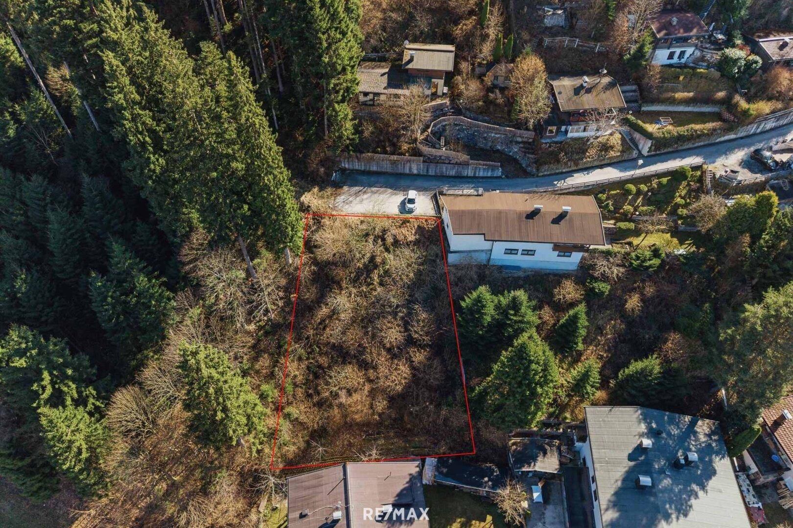 Senkrechte Luftaufnahme des Grundstücks, umgeben von dichtem Wald und einer Zufahrtsstraße.