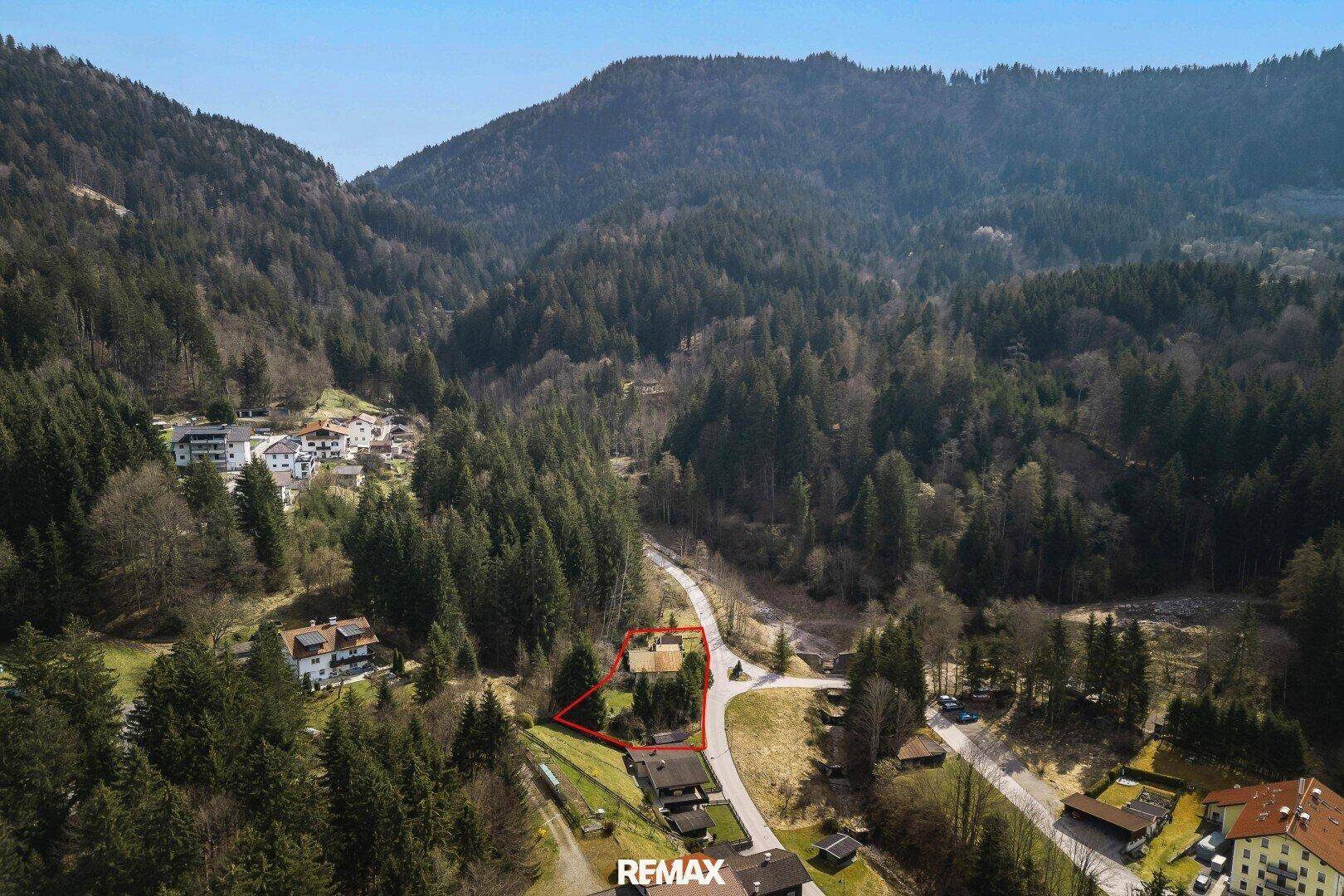 Panoramablick auf das Anwesen in einem Tal, umgeben von Wäldern und Bergen, mit weiteren Häusern in der Ferne.