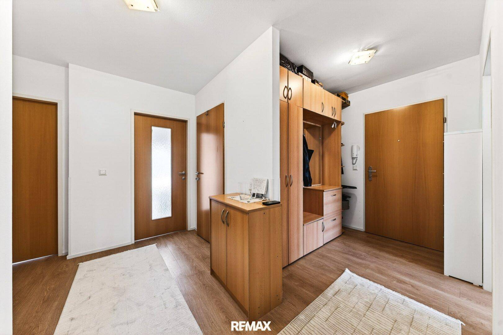 Geräumiger Flur mit Holzmöbeln und Garderobe, der zu verschiedenen Zimmern führt.