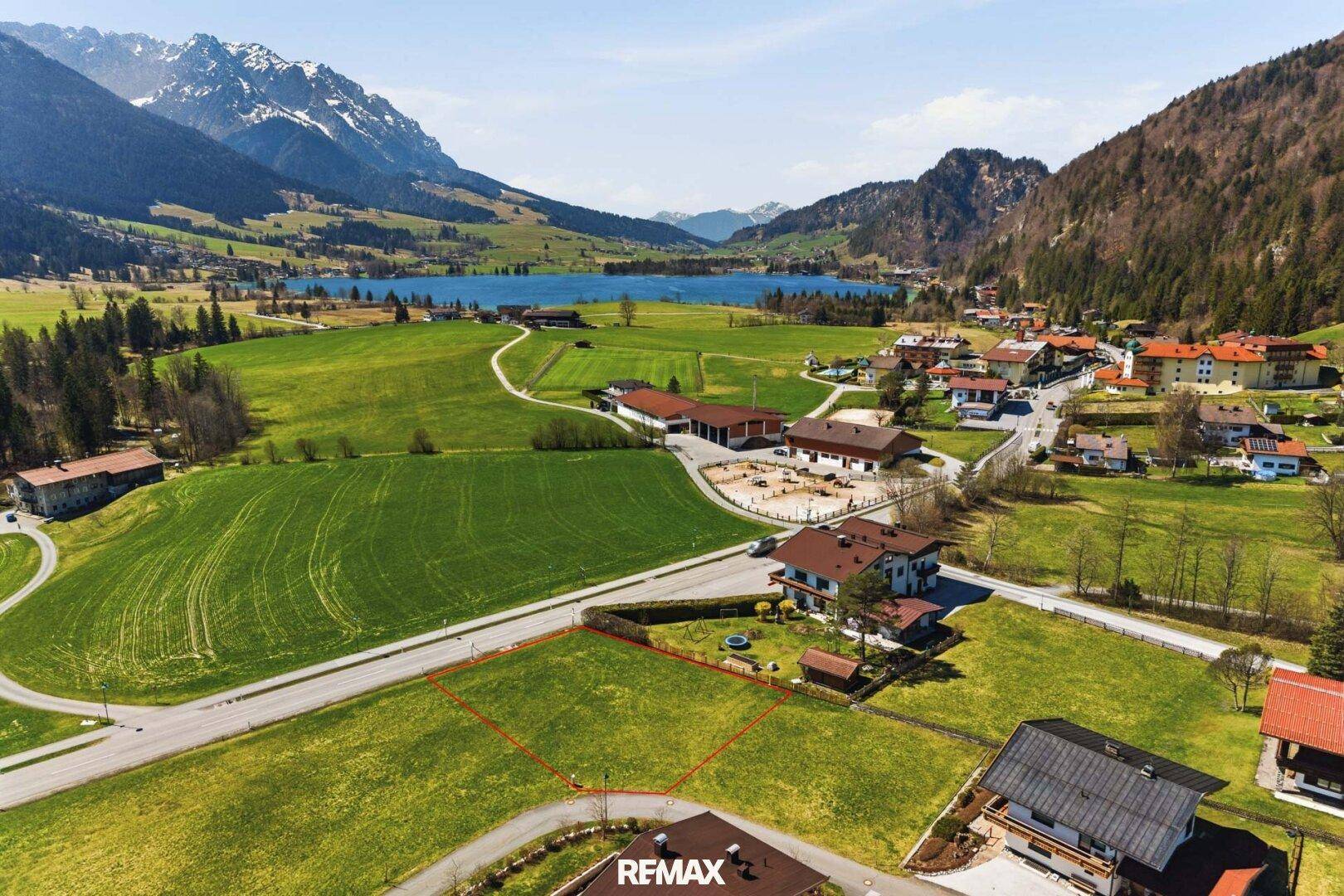 Panoramablick auf das Baugrundstück mit See, Bergen und umliegender Naturlandschaft.