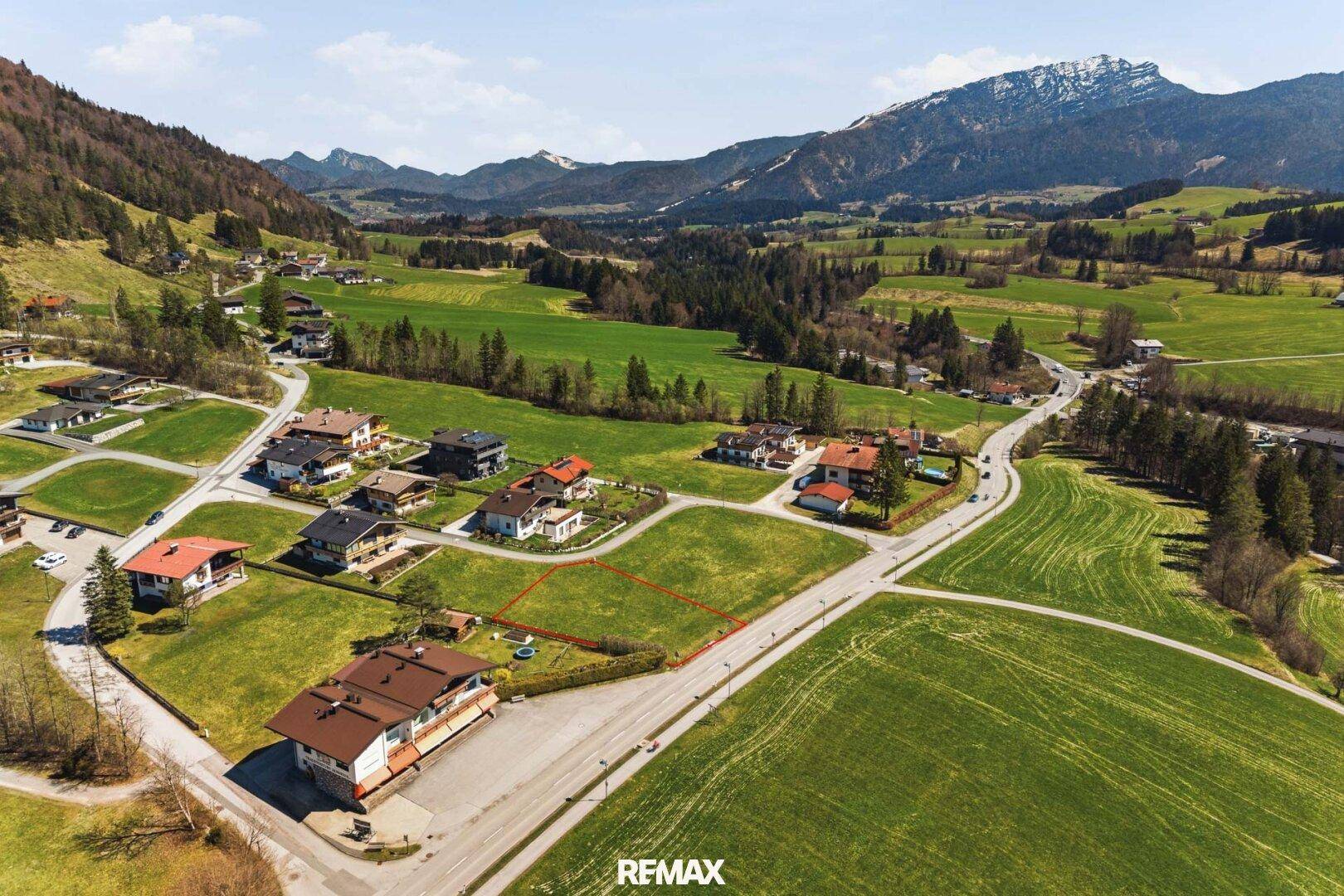 Weitläufige Ansicht des Baugrundstücks innerhalb einer ländlichen Siedlung mit Bergpanorama.