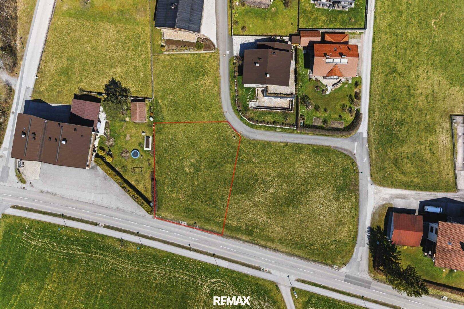 Nahaufnahme des Baugrundstücks von oben, umgeben von Wiesen und angrenzenden Häusern.