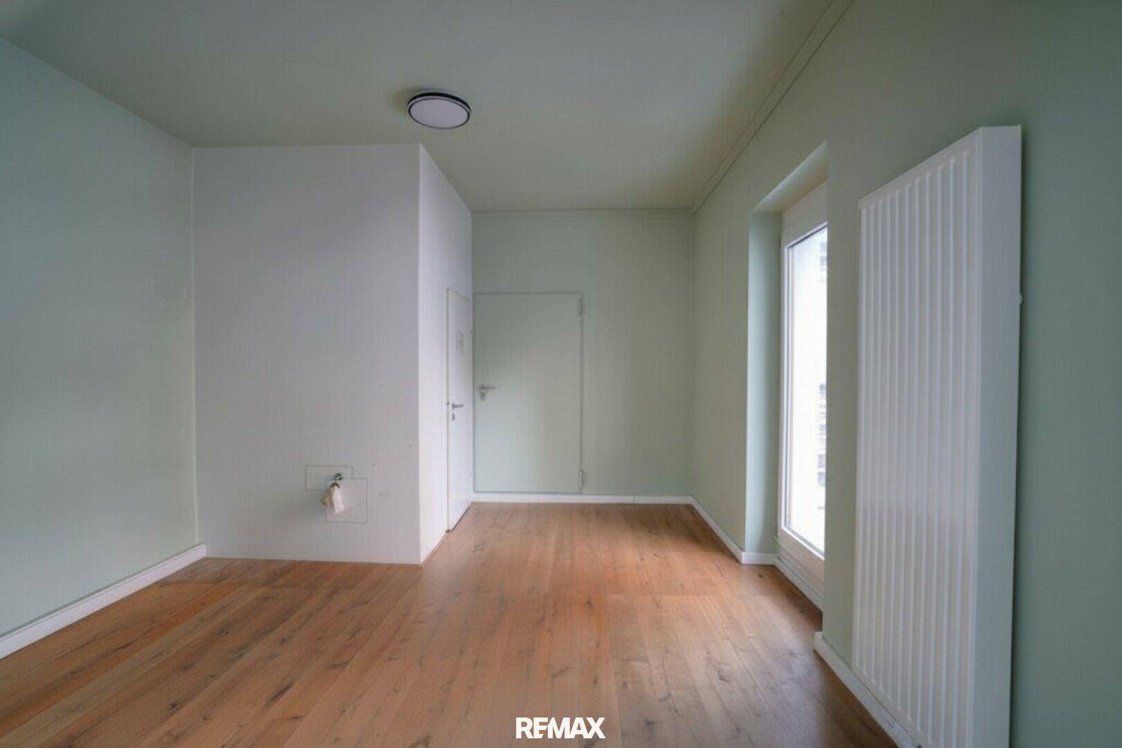 Heller Raum mit Holzboden und einer Tür, möglicherweise ein separates Büro oder Lager.