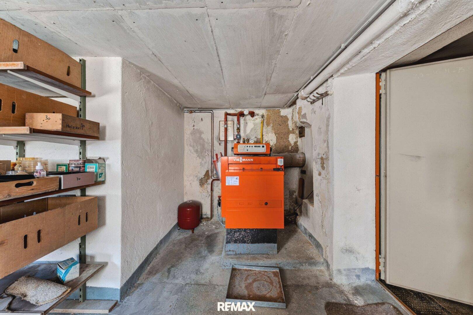 Hauswirtschaftsraum im Keller mit Heizungsanlage, Regalen und einem robusten Betonboden.