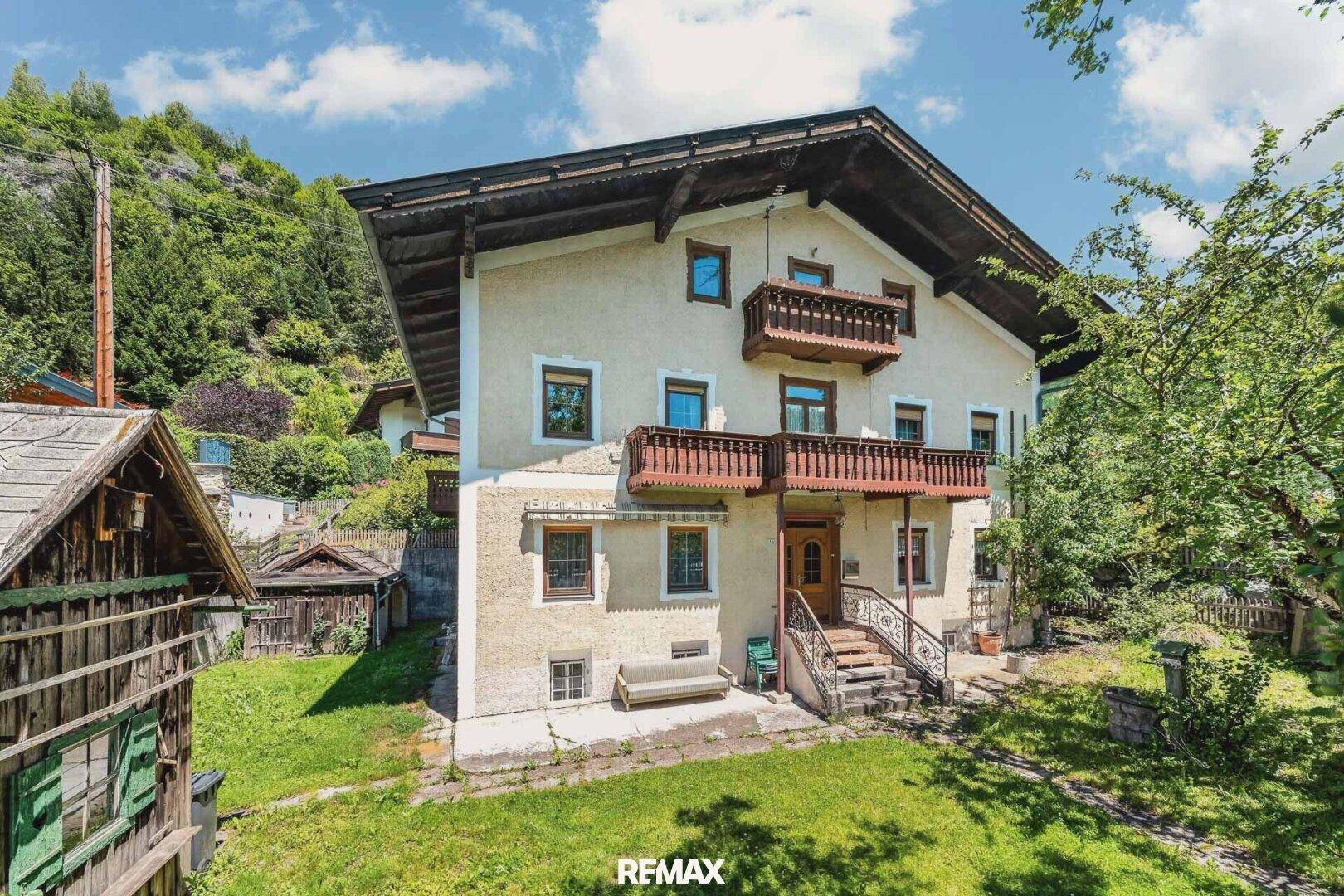 Traditionelles Haus mit mehreren Balkonen und einem gepflegten Gartenbereich im Vordergrund.