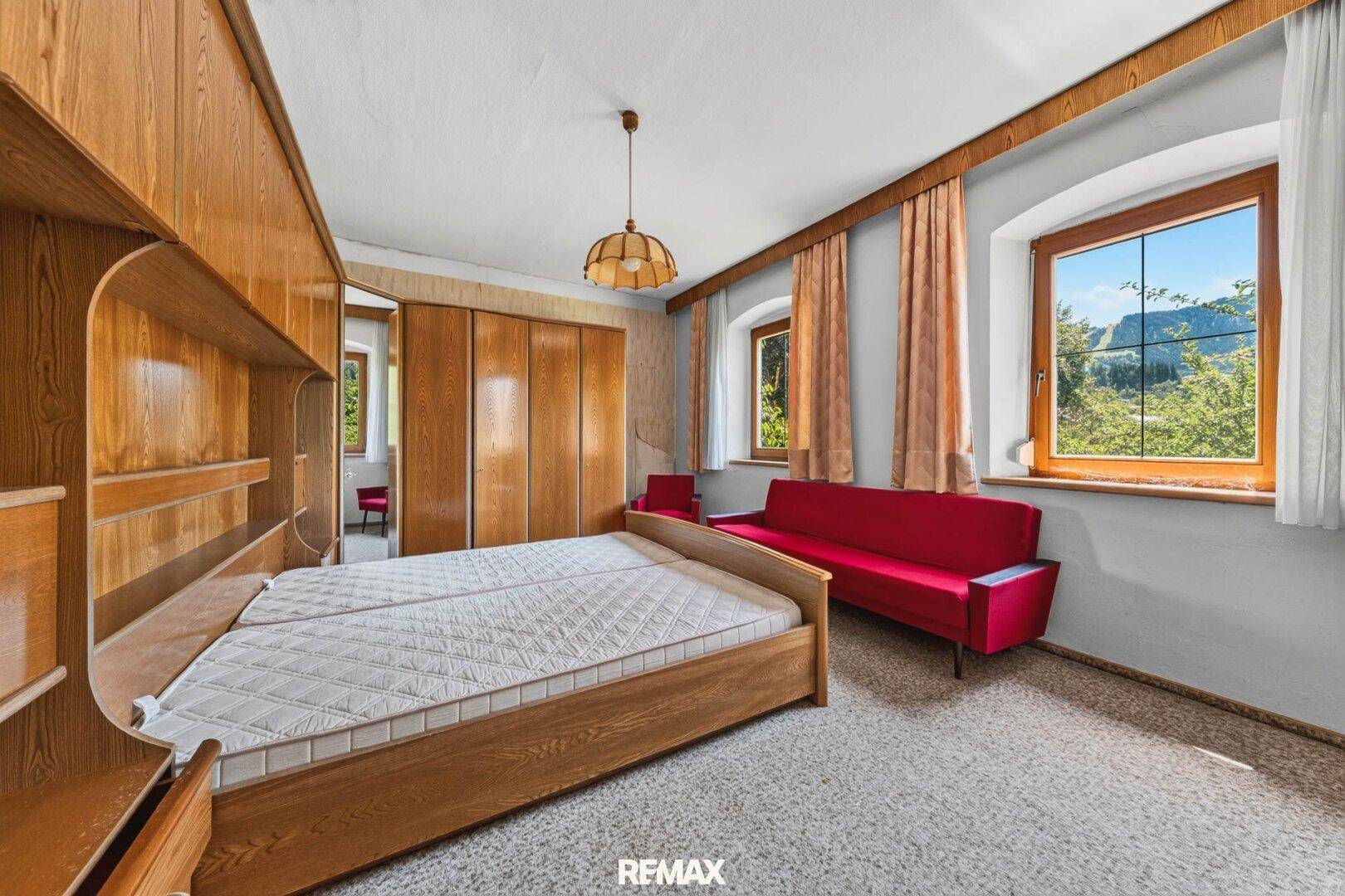 Schlafzimmer mit Doppelbett, Einbauschränken aus Holz und Blick auf die Berge.