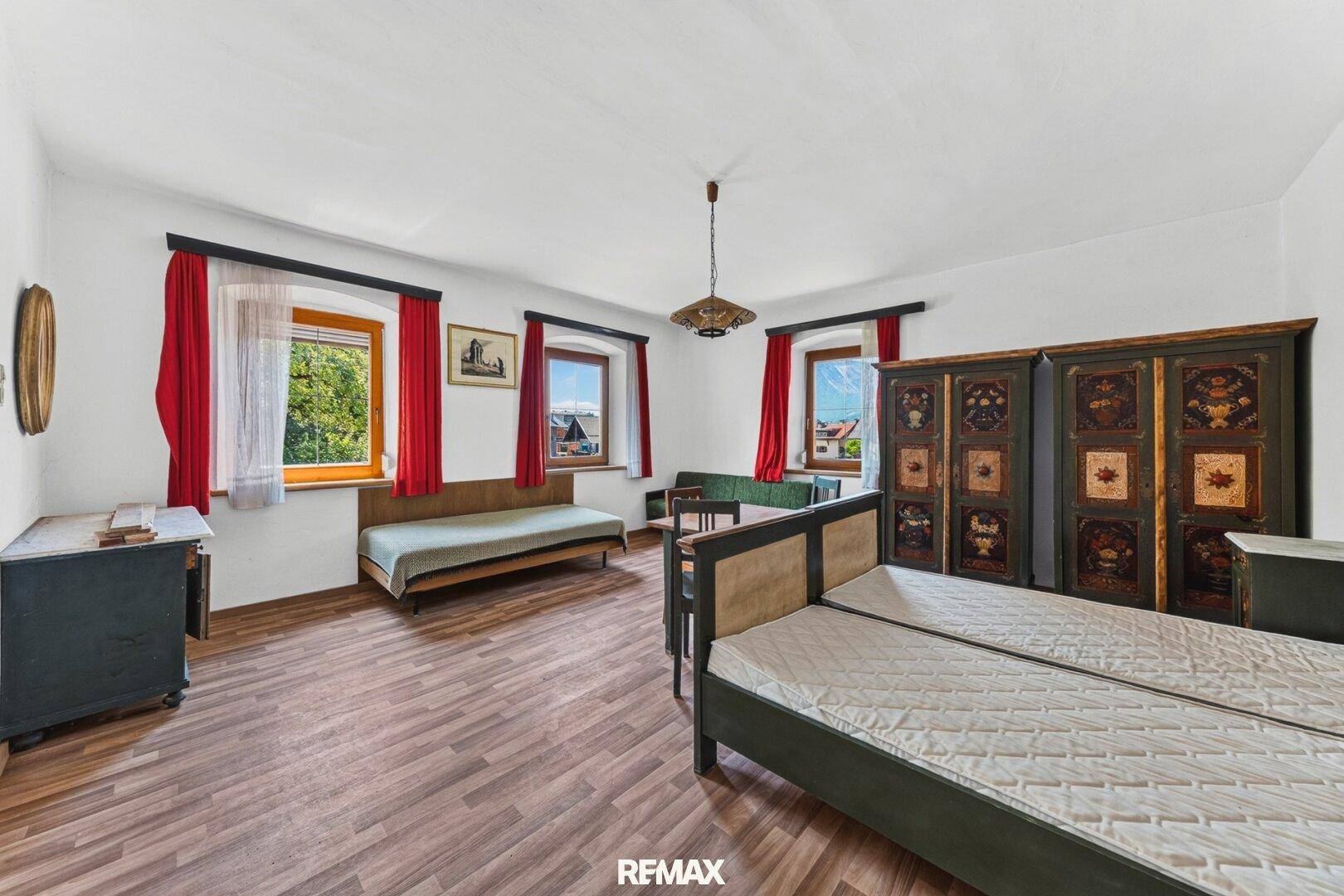 Geräumiges Schlafzimmer mit zwei Einzelbetten, Holzboden und traditionellen Möbeln.