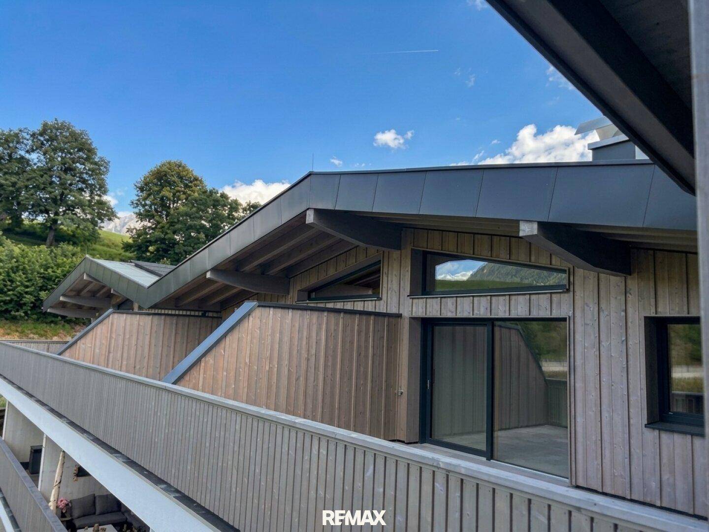 Moderne Holzfassade des Gebäudes mit mehreren Terrassen und Balkonen, eingebettet in die Berglandschaft.