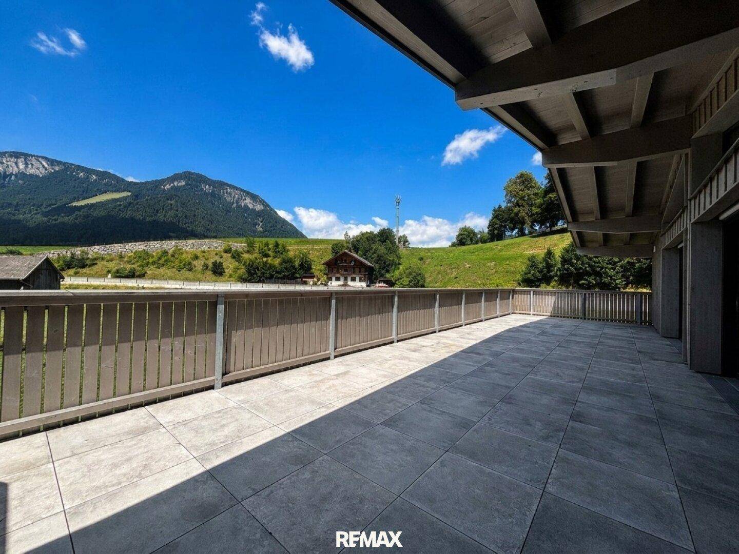 Weitläufige Terrasse mit Fliesenboden und atemberaubendem Panoramablick auf die Berge und grüne Landschaft.