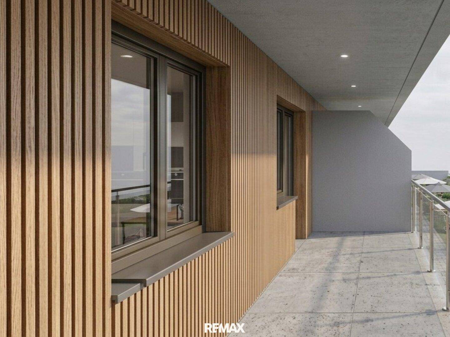 Moderner Balkon mit Holzverkleidung, Betonboden und Glasgeländer, ideal für entspannte Stunden.