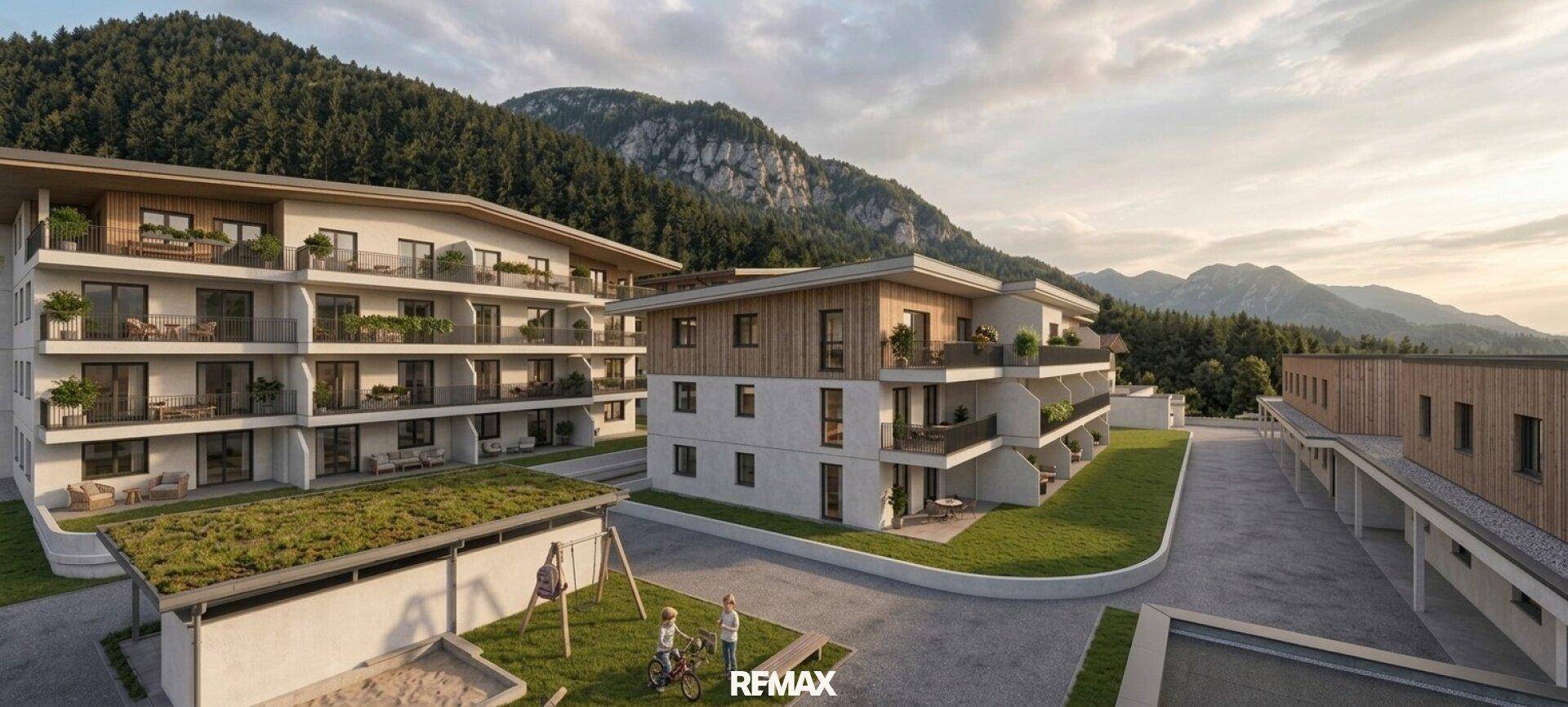 Moderne Wohngebäude in alpiner Landschaft mit Bergblick und einem Spielplatz für Kinder.