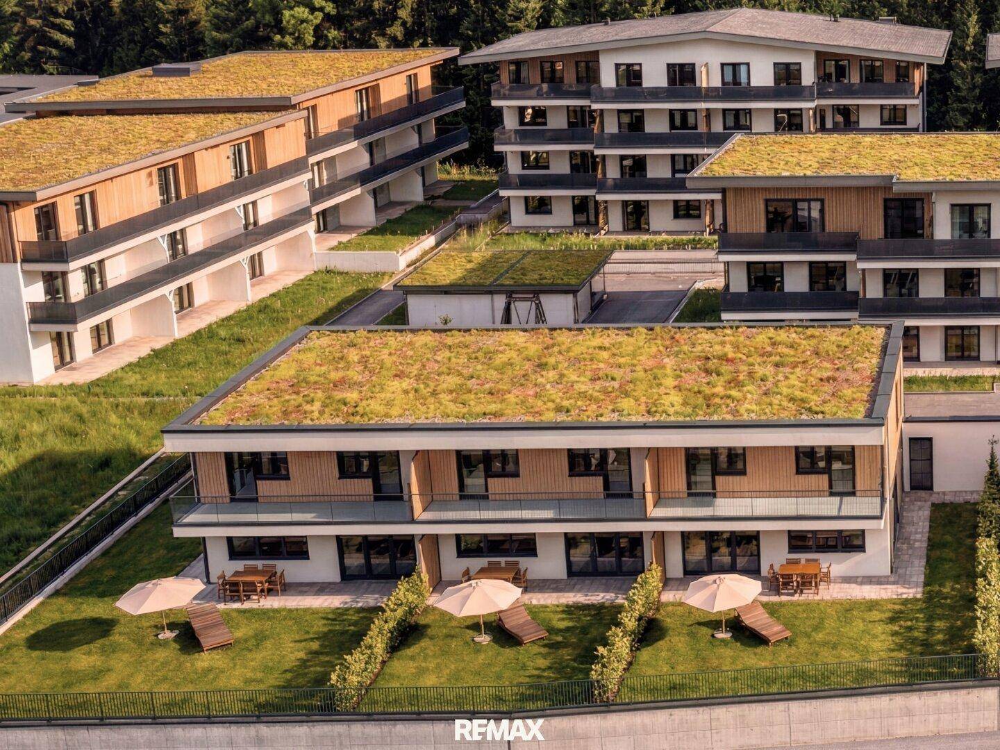 Moderne Wohngebäude mit begrünten Dächern und privaten Terrassenbereichen in einer grünen Umgebung.