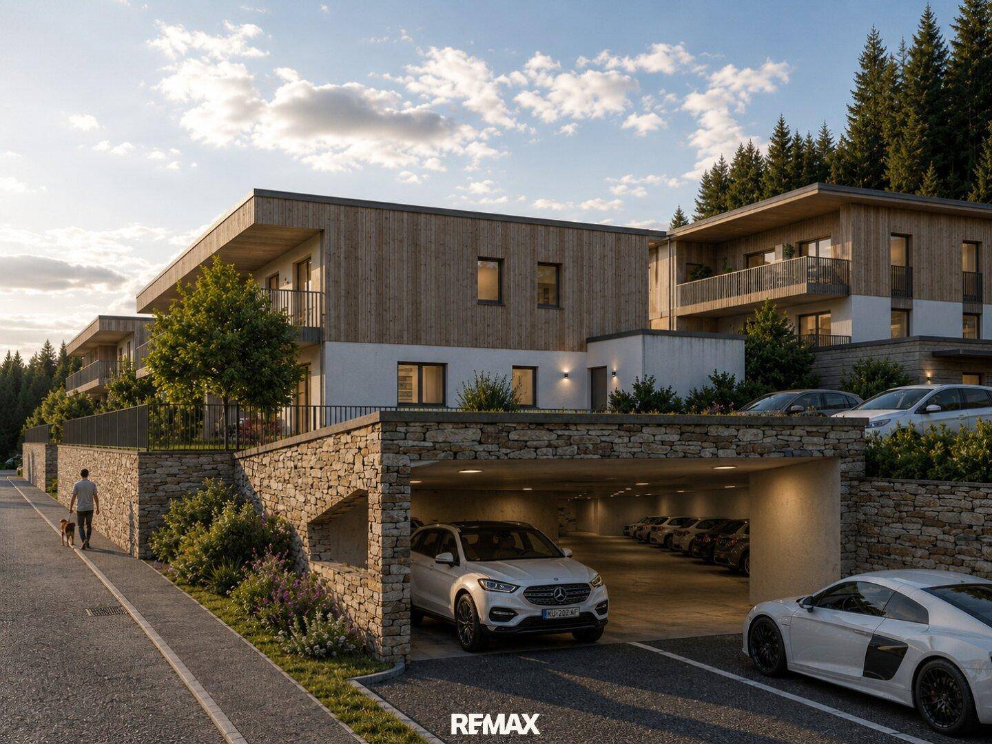 Moderne Wohnanlage mit Tiefgaragenzufahrt, umgeben von Natursteinmauern und gepflegter Bepflanzung.