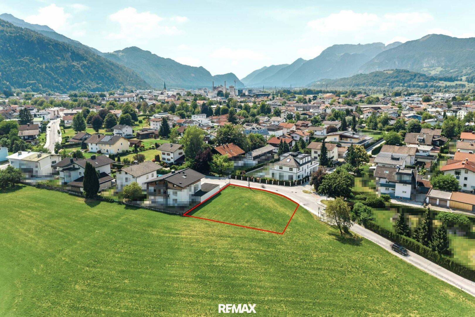 Luftaufnahme eines freien Baugrundstücks in einer malerischen Landschaft mit Bergen.