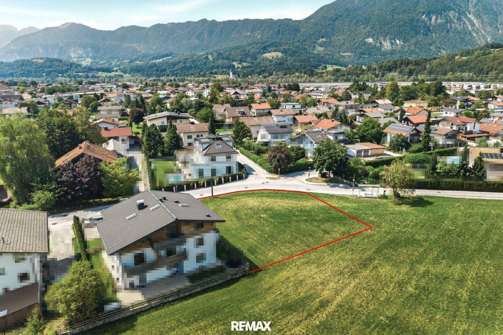 Blick von oben auf ein freies Grundstück in ländlicher Umgebung mit Bergpanorama.